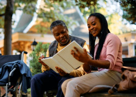 caretaker read a book to elderly man