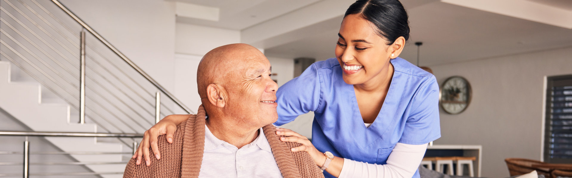 aide and elderly man smiling at each other